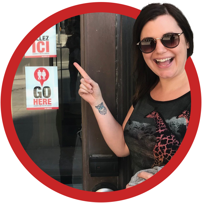 Justine pointing to a GoHere decal on a storefront