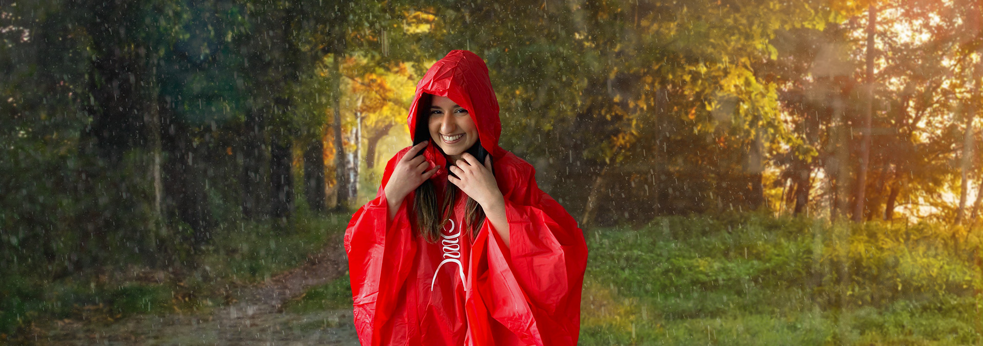 Une fille souriant vêtu d'un poncho de pluie rouge sur un fond de forêt pluvieuse.