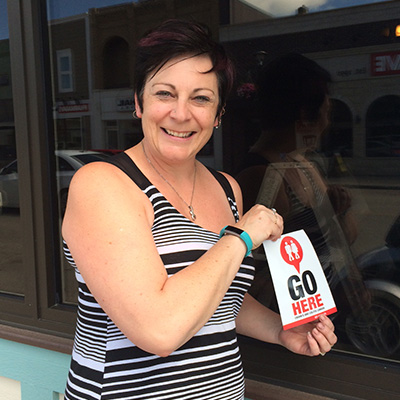 Lady placing a GoHere decal on a storefront