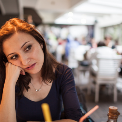 Une femme assise dans un café, regardant vers le bas