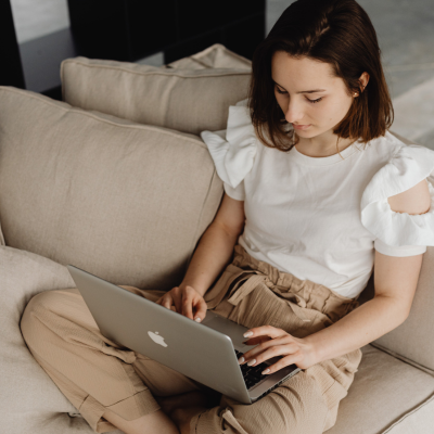 Femme assise sur un canapé devant un ordinateur portable